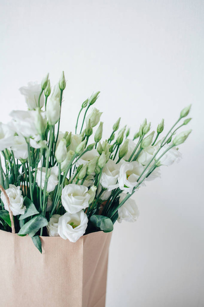 Beyaz eustom buket. Çiçekler yakın çekim. Yaprakları. Beyaz yaprakları. Hassas. Düğün çiçekleri. Çiçek teslim. Eko-paket. Bir kağıt torba çiçeklenir. Eko-ambalaj. Çiçekler kutusunda. - Fotoğraf, Görsel