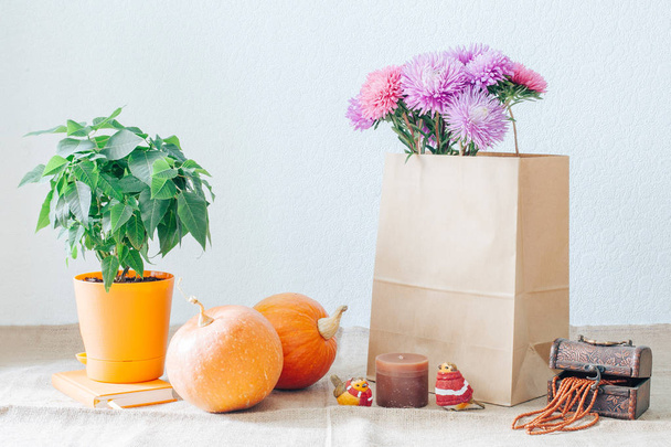 Bouquet of asters on the table in a vase and orange pumpkins. Autumn shopping. - Photo, Image