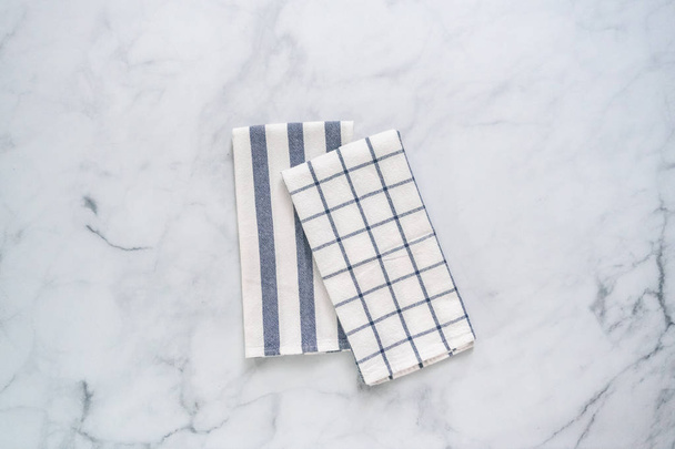Новые кухонные полотенца с простым голубым рисунком сложены на мраморном столе
. - Фото, изображение