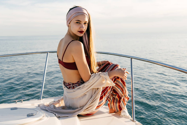 attractive stylish girl enjoying the sunset and sea on her yacht, posing - Fotó, kép
