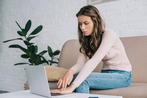 young woman having pain in hand while using laptop at home - Photo, Image