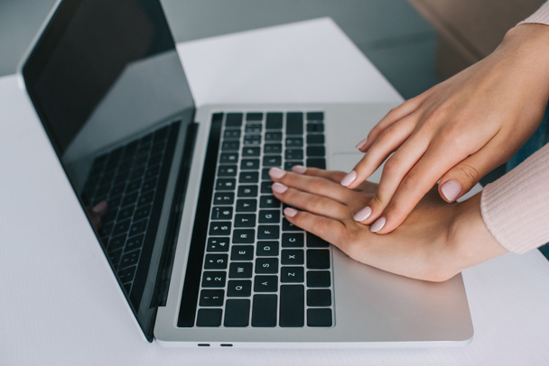 Nahaufnahme Teilansicht einer Frau, die sich bei der Benutzung eines Laptops mit leerem Bildschirm die Hand reibt - Foto, Bild
