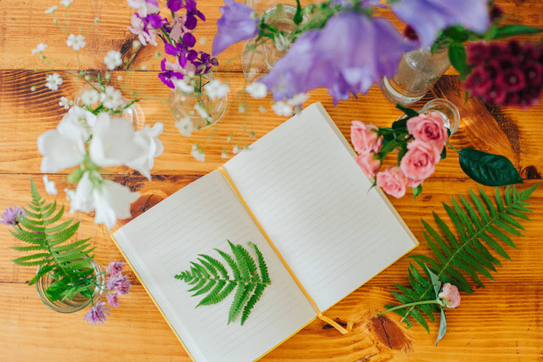 Beautiful composition with perfume samples and flowers on table. Flowers in flasks. Wildflowers. Summer bouquet. Open notebook. Botanical. - Photo, Image