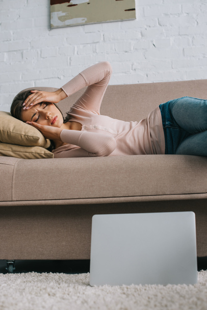 young woman with headache lying on sofa at home - Фото, зображення