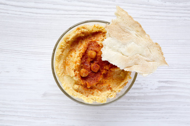 Bowl of Hummus iwith spices and pita bread on a white wooden surface, top view. Close-up.  - Photo, Image
