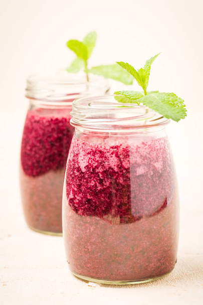 Blueberry smoothie decorated with fresh green mint leaves - transparent jars of summer blended vitamin cocktail on yellow pastel background. Berry shaked juice for healthy food concept. - Foto, Imagem