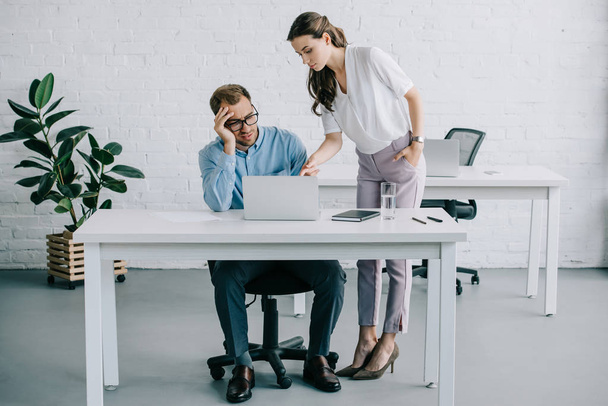 young businessman suffering from headache while working with female colleague in office - Foto, imagen
