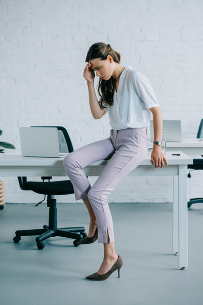young businesswoman sitting on table and suffering from headache in office - Foto, Imagen