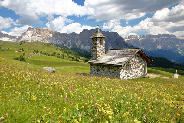 A Capela de Mastle localizado perto Raiser Pass, com Puez Odle gama de montanhas (à esquerda) e Sella Group montanhas (à direita) e com flores coloridas em primeiro plano, Val Gardena, Dolomitas, Itália
 - Foto, Imagem