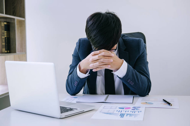 Businessman depressed and exhausted, businessman at his desk frustrated with problems with a pile of work and keeping eyes closed while sitting in workplace at office, Feeling sick and tired. - Photo, image