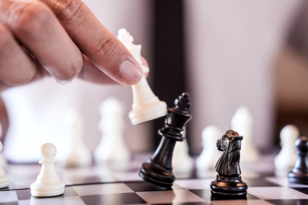 自信を持ってビジネスマン使用の手王チェスピース ホワイト転覆をクラッシュにチェスのゲームをプレイ、反対チーム開発分析新しい戦略計画、勝利と成功のためのビジネス戦略. - 写真・画像