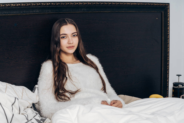charming sleepy girl with long hair sitting in bed late at night, resting and wanting to sleep - Photo, Image