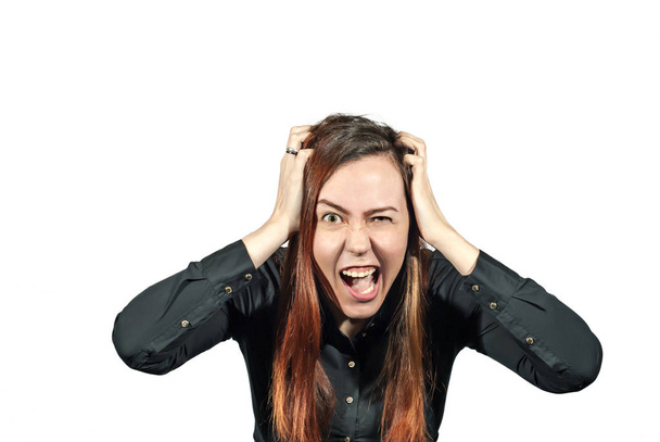 Girl on a white background with extreme expression on her face clasped her hands in her own hair and screams. Stress or hysterics. - Photo, Image