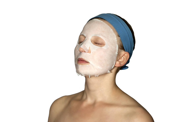 junge Frau mit geschlossenen Augen mit Kosmetikmaske aus Papier im Gesicht - Foto, Bild