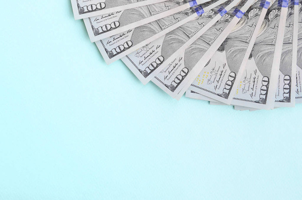 Fan van een US dollar biljetten van een nieuw ontwerp ligt op een lichtblauwe achtergrond. - Foto, afbeelding