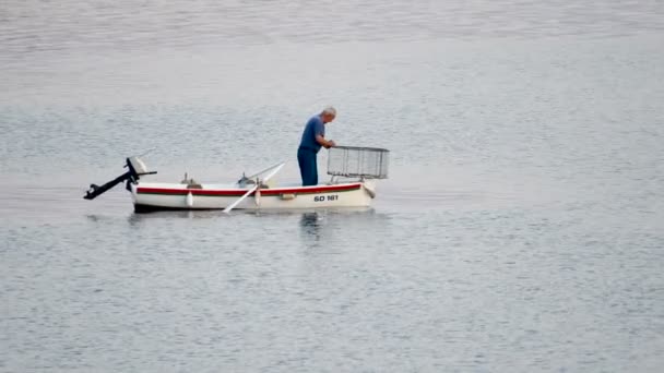 Vecchio pescatore tradizionale in Croazia su una piccola barca di legno cattura di pesce con gabbia da pesca, baccello, zoom in
 - Filmati, video