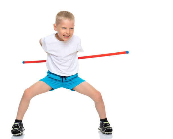 Un niño lindo con una camiseta blanca limpia muestra los ejercicios que hace cuando practica fitness. El concepto de la publicidad de artículos deportivos, es posible inscribirse en una camiseta blanca. Aislado en - Foto, imagen