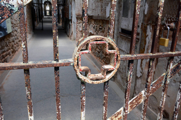 Simbolo della croce medica nei bar di un blocco cellulare ospedaliero della prigione abbandonata
 - Foto, immagini