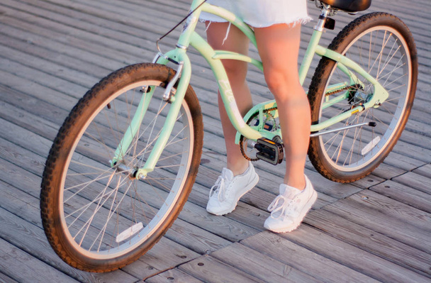 Close up, bela jovem com bicicleta, guidão, rodas, parte do corpo. Mãos no guiador
 - Foto, Imagem