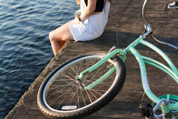 Close-up, mooie jonge vrouw met fiets, stuur, wielen, lichaamsdeel. Handen op het stuur - Foto, afbeelding