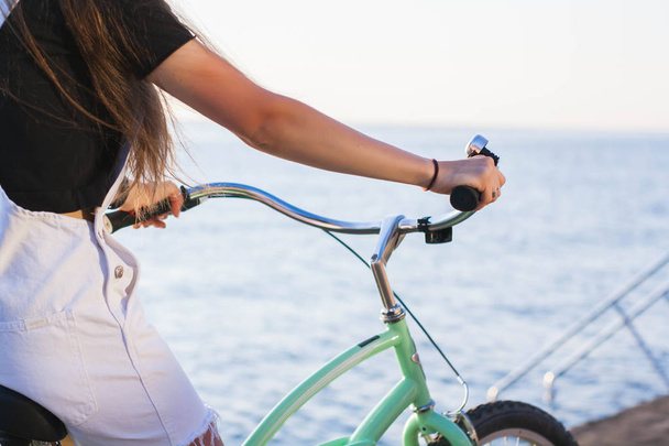 Close up, beautiful young woman with bicycle, handlebar, wheels, body part. Hands on the handlebar - Foto, imagen