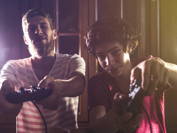 kaksi mies pelata konsoli peli yöllä pimeässä huoneessa joystick peliohjain
  - Valokuva, kuva