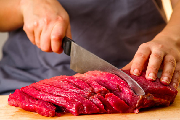 woman cuts fresh meat in the kitchen - Photo, Image