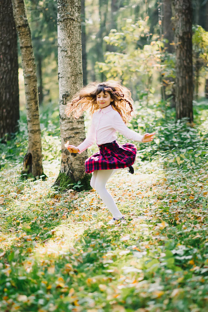 happy beautiful brunette girl is spinning and enjoying herself in the Park - Фото, изображение