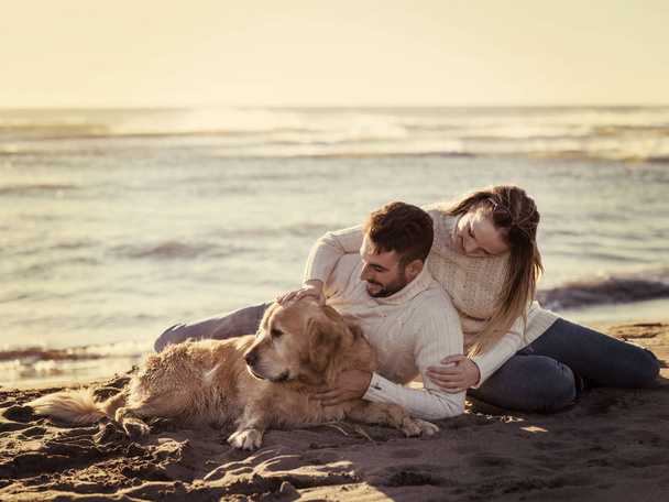 Couple With A Dog enjoying time  together On The Beach at autumn day colored filter - Фото, изображение