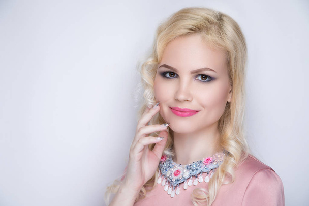 Young glamour girl. Sexy woman, blonde hair-do, pink blouse, crimson lips lip-gloss lipstick.  Fashion blond princess with pink make up, professional manicure. Fingers touch face. Massive jewellery - Valokuva, kuva
