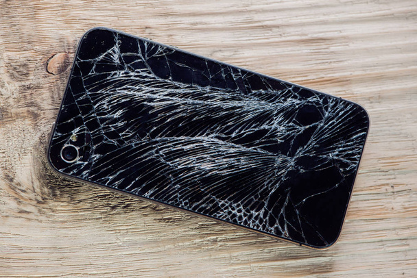 Smartphone display with broken glass on a wodden table. - Foto, immagini