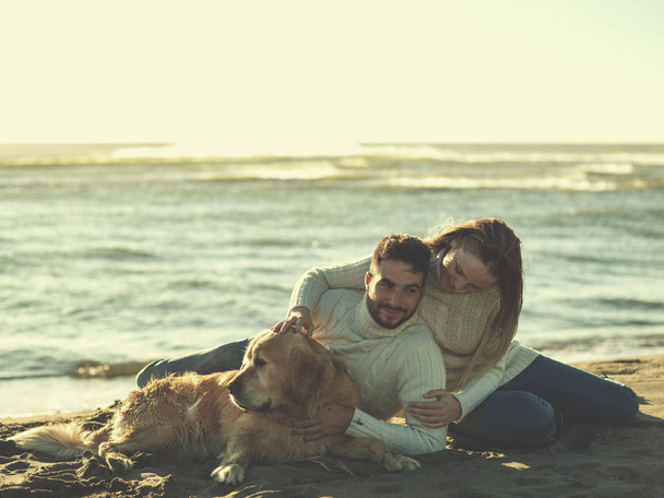 Couple With A Dog enjoying time  together On The Beach at autumn day colored filter - Foto, imagen