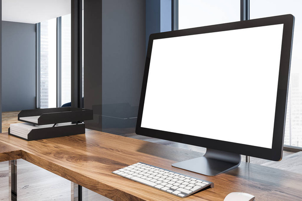 Blank computer screen standing on a wooden table in an office interior situated in a blue wall loft room. Side view. 3d rendering mock up - Фото, изображение