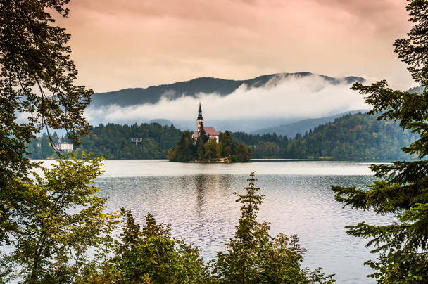 Bled Lake Slovenië. Bergmeer met klein eiland, kerk en kleurrijke hemel, gestileerde zonsopgang. - Foto, afbeelding
