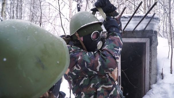 Człowiek w mundurze w masce gazowej w zimowym lesie. portret młodego żołnierza w masce gazowej na tle przyrody. - Zdjęcie, obraz