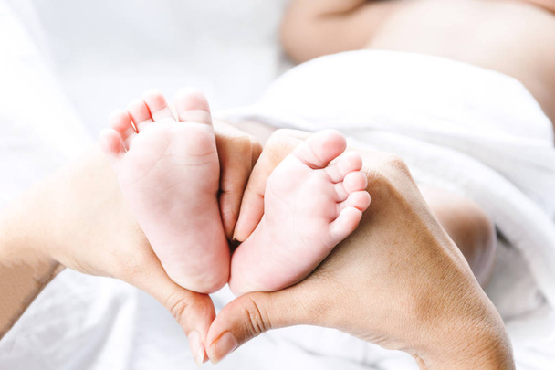 Bebé recién nacido pies en las manos madre
 - Foto, imagen