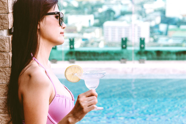 Yüzme havuzunda yaz tatile rahatlatıcı resort spa adlı kokteyl içme bikini giyen kadın - Fotoğraf, Görsel