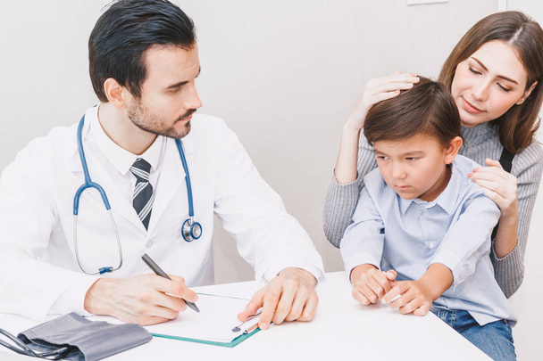 Лікар перевіряє інформацію з маленьким хлопчиком та мамою на столі лікарів у лікарні. Охорона здоров'я та медицина
 - Фото, зображення