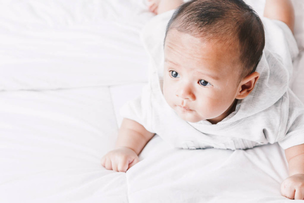 Portrait de bébé relaxant sur lit blanc dans la chambre
 - Photo, image