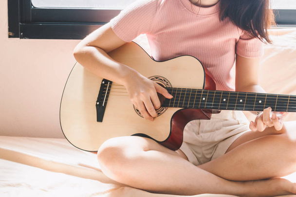 Woman playing a guitar on bed - Foto, afbeelding