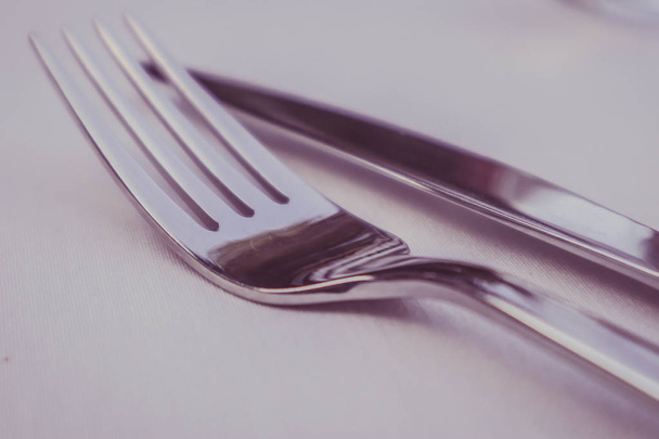 Elegant shiny fork and knife. Luxury restaurant cutlery set on the tablecloth. - Φωτογραφία, εικόνα