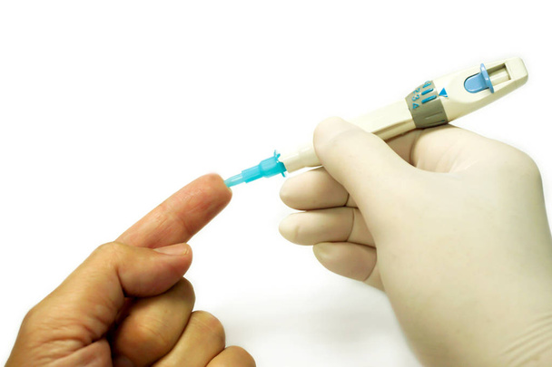 Рука лікаря в білій медичній рукавичці, що тримає голчасту ручку на людському пращурі, щоб перевірити глюкозу в крові ізольовано на білому тлі
. - Фото, зображення