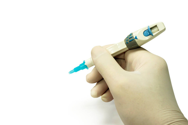 Mão de perto do médico de luva médica branca segurando caneta agulha para verificação de glicose no sangue isolado em fundo branco e fazer com caminhos
. - Foto, Imagem