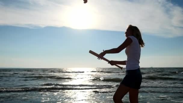 Zeitlupe: junges sexy Mädchen schlägt Baseballschläger mit Gemüse und Tomatenfrüchten. es liegt am Strand, Sandstrand. - Filmmaterial, Video