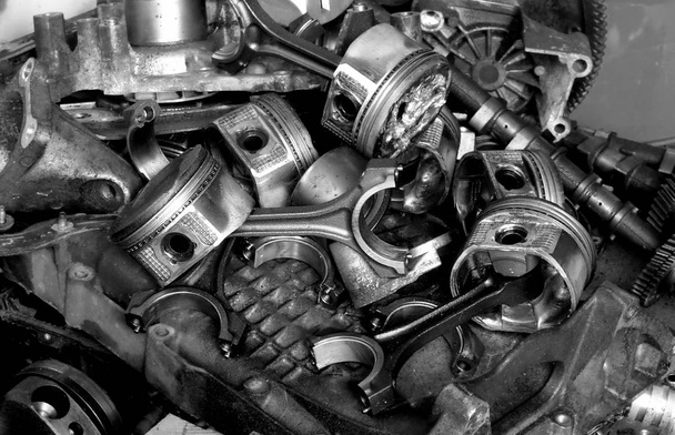 a motor és a részek fém dugattyú szétszórt a garázsban, a javítások, ahol autók begyűjtésére, a téma az autók javítása - Fotó, kép