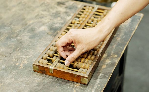 Mano de la persona que juega y demostración usada del ábaco chino antiguo en la tabla negra vieja de madera
. - Foto, imagen