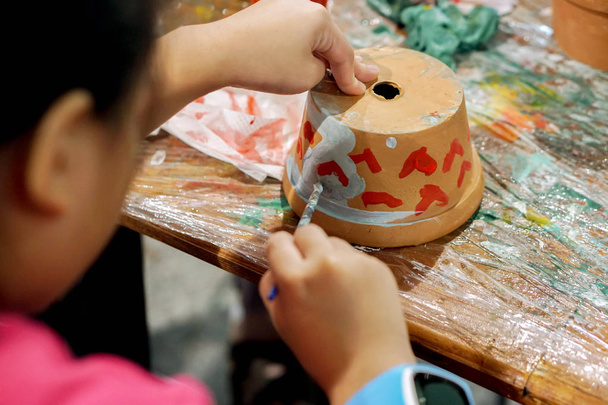 Azjatycki dziewczynka badania i uczenia się farby na Doniczka w jej szkole, w klasie sztuki. - Zdjęcie, obraz