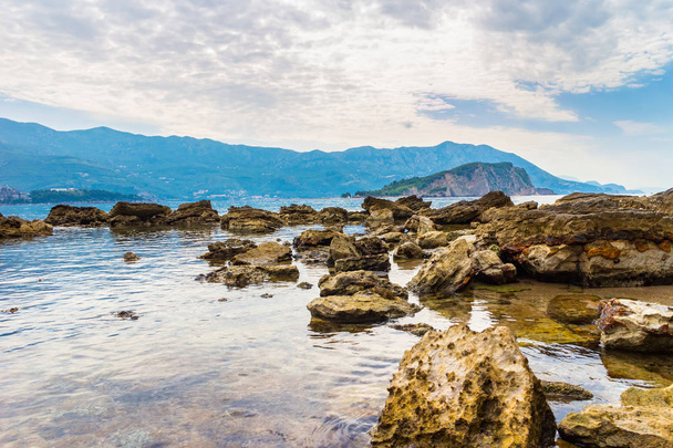 Παραλία Μογκρέν με μεγάλες πέτρες και νησίδα Σβέτι Νικόλα στην Αδριατική θάλασσα στο Μαυροβούνιο. - Φωτογραφία, εικόνα