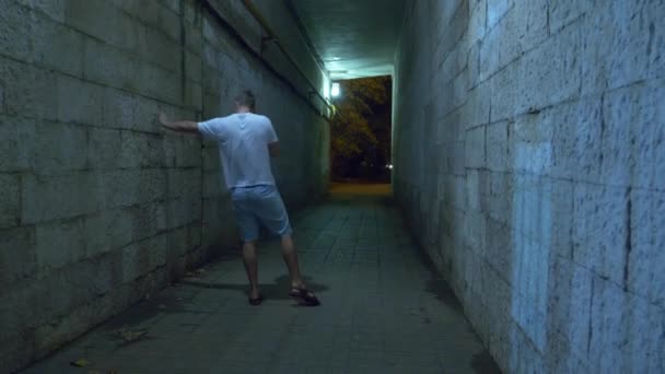 Pijany człowiek idzie sam w nocy przez tunel dla pieszych. 4k. - Materiał filmowy, wideo
