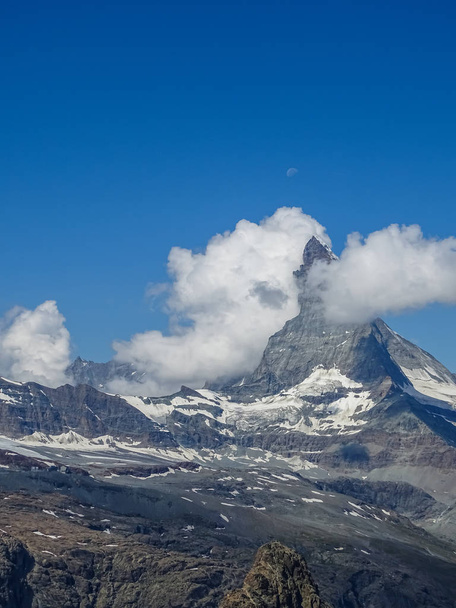 moon shining over the famous matterhorn with clouds and blue sky switzerland - Photo, Image